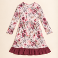 A long-sleeve children's dress with a pink and red floral print on a cream background, featuring a gathered waist and a contrasting dark red ruffled hem, laid flat on a light beige background.