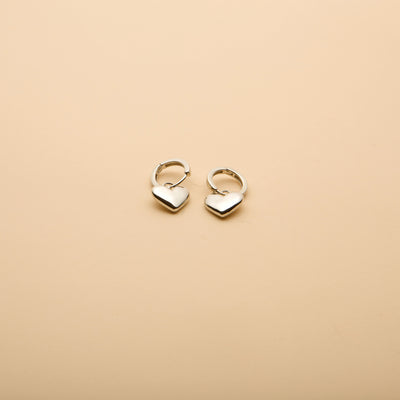 Silver heart charm hoop earrings with a timeless, elegant design, perfect for everyday wear and effortless style.