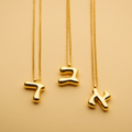Three gold Hebrew letter pendant necklaces with a polished finish, offering a timeless, meaningful design for everyday wear and thoughtful gifting.