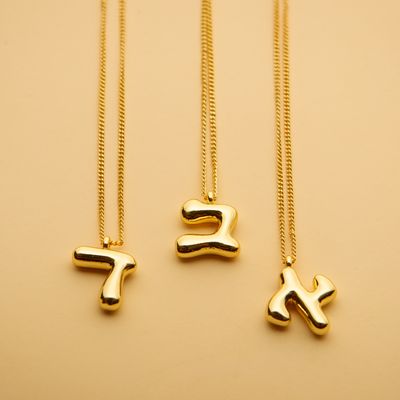 Three gold Hebrew letter pendant necklaces with a polished finish, offering a timeless, meaningful design for everyday wear and thoughtful gifting.