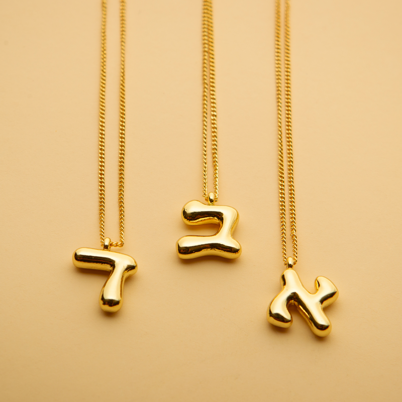 Three gold Hebrew letter pendant necklaces with a polished finish, offering a timeless, meaningful design for everyday wear and thoughtful gifting.