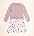 A children's long-sleeve dress laid flat on a warm cream background. The top half is a solid dusty mauve/lavender sweatshirt-style panel, and the bottom half is a white skirt with an allover feather print in pink, red, and dark brown tones.